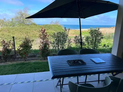 a table with chairs and an umbrella on a patio at Bravone 74- piscine en résidence-clim-wifi-pieds dans l'eau in Linguizzetta