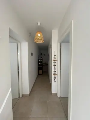 a hallway with white walls and a chandelier at Bravone 74- piscine en résidence-clim-wifi-pieds dans l'eau in Linguizzetta