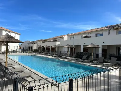 a swimming pool with chairs and umbrellas next to a building at Bravone 74- piscine en résidence-clim-wifi-pieds dans l'eau in Linguizzetta