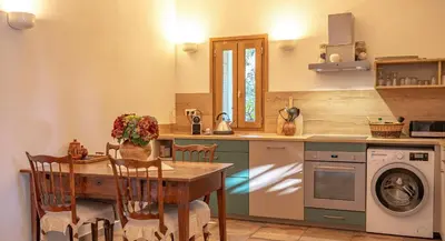 a kitchen with a table and a washing machine at I Carbonni - Bergerie 80m2 entre mer et montagne in Sotta
