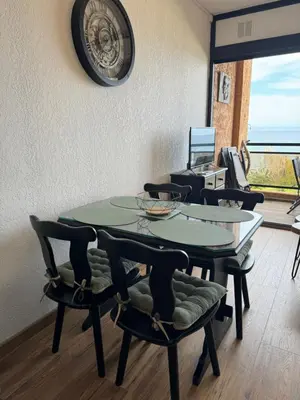 a table with chairs and a clock on the wall at Appartement n 302 moriani plage in Moriani Plage