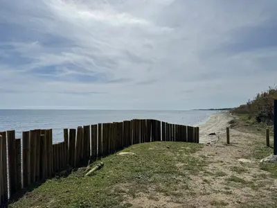 a wooden fence on a beach next to the ocean at Appartement n 302 moriani plage in Moriani Plage