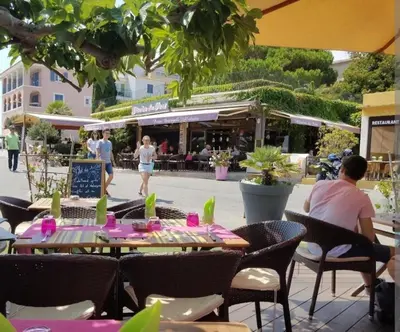 a group of people sitting at an outdoor restaurant at Palmeraie102 in Sari Solenzara