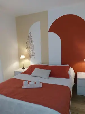 a bedroom with a large bed with red and white sheets at Palmeraie102 in Sari Solenzara