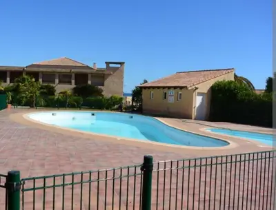 a swimming pool in front of a house at Palmeraie102 in Sari Solenzara