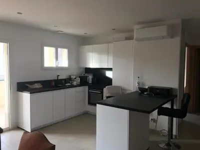 a kitchen with white cabinets and a black counter top at Appartement à Ghisonaccia-Prunelli in Prunelli-di-Fiumorbo
