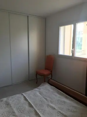 a bedroom with a red chair and a window at Appartement à Ghisonaccia-Prunelli in Prunelli-di-Fiumorbo