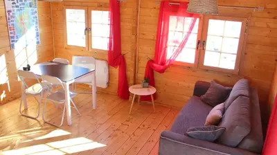 a living room with a couch and a table and windows at Les Chalets De Lozzi in Calacuccia