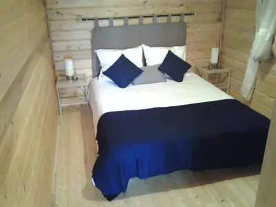 a bedroom with a large bed with blue pillows at Les Chalets De Lozzi in Calacuccia