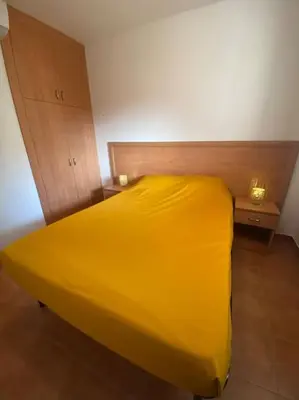 a yellow bed in a room with two night stands at Appartement en bord de mer avec piscine in San-Nicolao