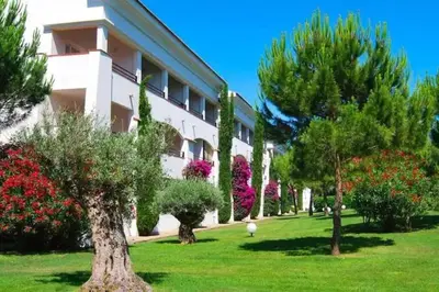 a building with trees and flowers in a park at Appartement en bord de mer avec piscine in San-Nicolao