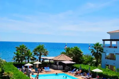 a resort with a swimming pool and the ocean at Appartement en bord de mer avec piscine in San-Nicolao