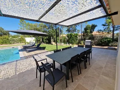 a patio with a table and chairs and a pool at Villa ALVALMAX in Porto-Vecchio
