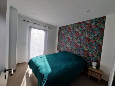 a bedroom with a green bed and a colorful wall at Villa ALVALMAX in Porto-Vecchio