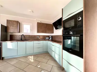 a kitchen with white cabinets and black appliances at Appartement ALERIA 2/4 personnes in Aléria