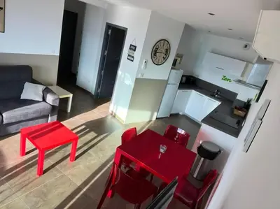 a living room with a red table and a couch at Appartement Sole - vue golfe de Porto Vecchio in Porto-Vecchio