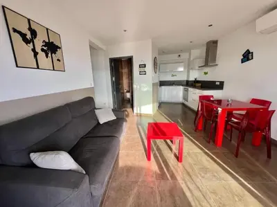 a living room with a black couch and a red table at Appartement Sole - vue golfe de Porto Vecchio in Porto-Vecchio