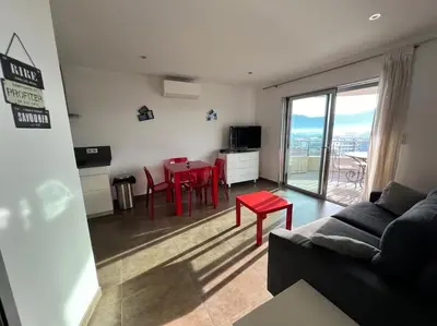 a living room with a couch and a red table at Appartement Sole - vue golfe de Porto Vecchio in Porto-Vecchio
