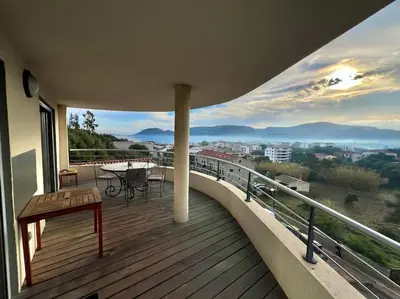 a balcony of a house with a table and a bench at Appartement Sole - vue golfe de Porto Vecchio in Porto-Vecchio