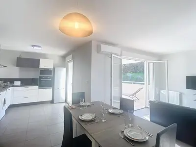 a kitchen and dining room with a table with plates on it at Bel appartement 2 chambres à Proximité des Commodités in Sarrola-Carcopino