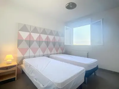 two beds in a small room with a window at Bel appartement 2 chambres à Proximité des Commodités in Sarrola-Carcopino