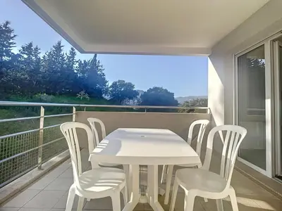 a white table and chairs on a balcony at Bel appartement 2 chambres à Proximité des Commodités in Sarrola-Carcopino