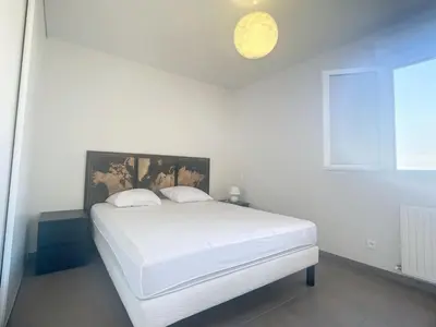 a white bedroom with a large white bed in it at Bel appartement 2 chambres à Proximité des Commodités in Sarrola-Carcopino
