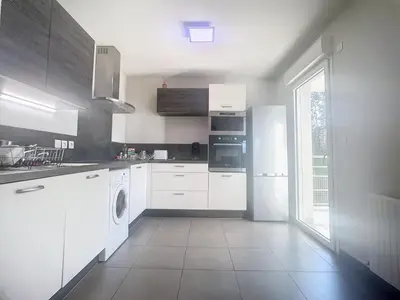 a kitchen with white appliances and a large window at Bel appartement 2 chambres à Proximité des Commodités in Sarrola-Carcopino