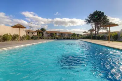 a large blue swimming pool with umbrellas at Villa moderne Cala Rossa Bay Les Oceanides in Lecci