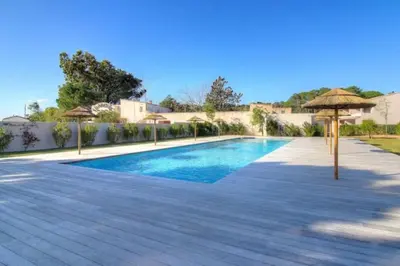 a swimming pool with an umbrella next to a house at Villa moderne Cala Rossa Bay Les Oceanides in Lecci