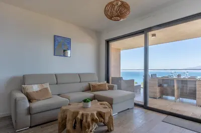 a living room with a couch and a table at Les Terrasses de l'Isolella - Vue mer et montagne in Pietrosella