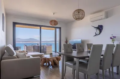 a dining room with a table and chairs and a dog at Les Terrasses de l'Isolella - Vue mer et montagne in Pietrosella