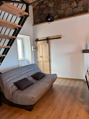 a large couch in a room with a ladder at chez lulu Appartement cosy. in Cozzano