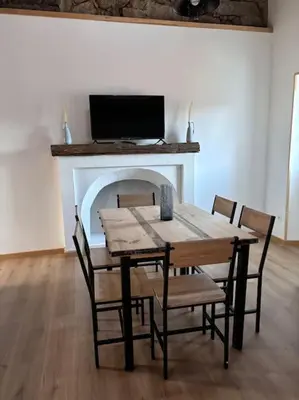 a dining room table with chairs and a fireplace at chez lulu Appartement cosy. in Cozzano