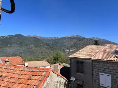 a view of roofs of buildings with mountains in the background at chez lulu Appartement cosy. in Cozzano