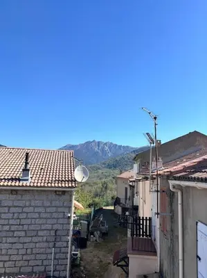 an alley between two buildings with mountains in the background at chez lulu Appartement cosy. in Cozzano
