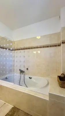 a bathroom with a tub with a glass wall at Maison en bord de mer, Plage de la Marana en Corse in Borgo