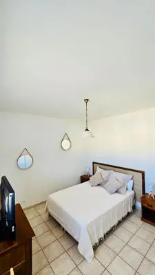 a bedroom with a white bed and a tv at Maison en bord de mer, Plage de la Marana en Corse in Borgo