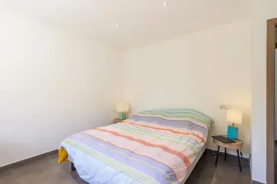 a white bedroom with a bed and two night stands at San Quilico - Maison climatisée piscine vue mer in Aregno