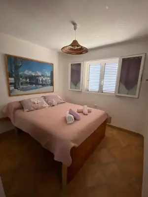 a bedroom with a large bed with pink sheets at Villa pour 4 personnes proche Santa Giulia in Sotta
