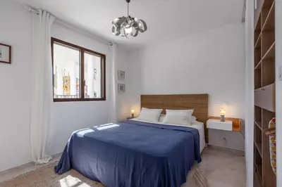 a white bedroom with a blue bed and a window at Magadhja Fiurita - Appt climatisé - Vue mer in Pietrosella