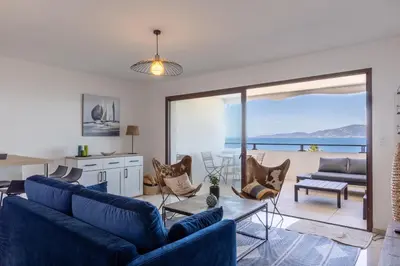 a living room with blue furniture and a view of the ocean at Magadhja Fiurita - Appt climatisé - Vue mer in Pietrosella