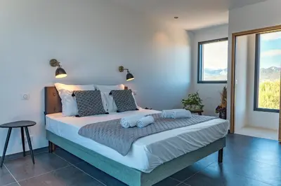 a bedroom with a large bed with blue pillows at Casa Campa di Pinarello in Sainte-Lucie de Porto-Vecchio