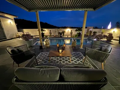 a patio with a couch and a table and a pool at Studio, piscine, 10 min des plages, Ajaccio, corse du sud, in Appietto