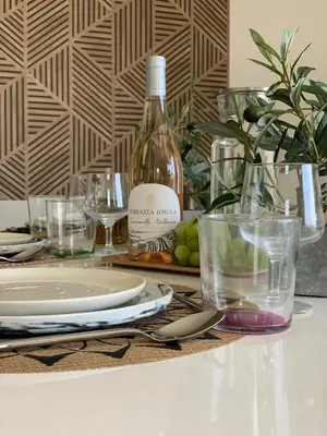a table with a bottle of wine and plates and glasses at Résidence 3 étoiles Pietra Gemina - Appartements de vacances, au calme, avec Piscine in Calenzana