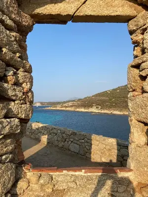 a window in a stone wall looking at the water at Résidence 3 étoiles Pietra Gemina - Appartements de vacances, au calme, avec Piscine in Calenzana