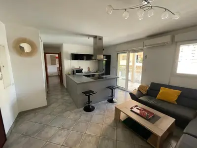 a living room with a couch and a kitchen at Immeuble le Mozart in Ajaccio