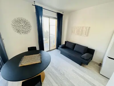 a living room with a table and a couch at Grand Studio terrasse vue sur mer et parking in Ajaccio
