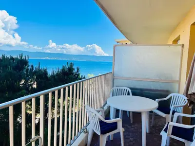 a balcony with a table and chairs and the ocean at Grand Studio terrasse vue sur mer et parking in Ajaccio