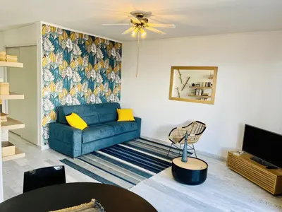 a living room with a blue couch and a tv at Grand Studio terrasse vue sur mer et parking in Ajaccio